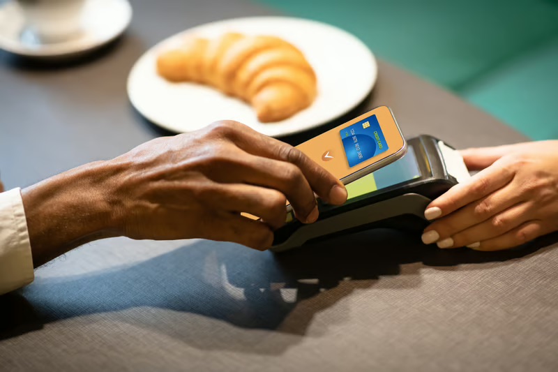 Customer using a smartphone to make a contactless cashless payment at a payment terminal.