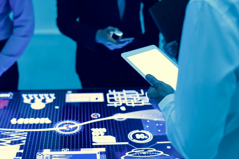 Business professionals using a tablet and digital interface to support digital transformation in legacy markets.