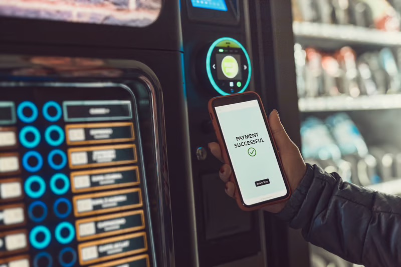 Customer using a smartphone for a successful mobile payment at an automated vending machine.